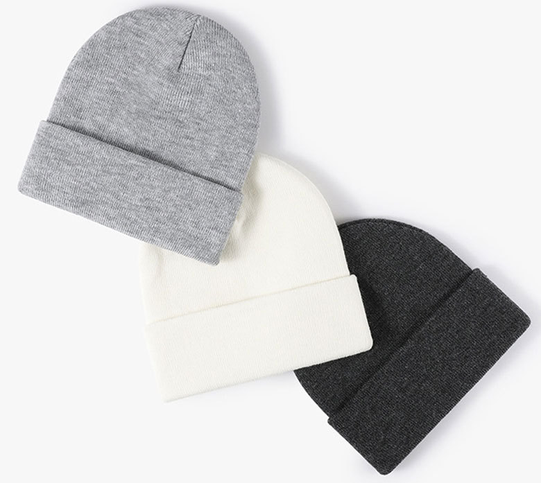 light grey, cream and charcoal heather cuffed beanies overlapped diagonally on white
