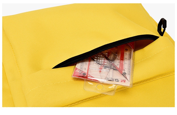 Yellow padded front panel with a half-open black coil zipper and a clear card sleeve tucked into the pocket, showing the flat-item storage zone on the bag face